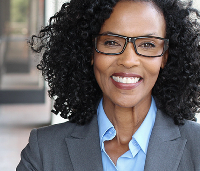 Black woman with glasses and suit coat representing people wo work in Finance or Shared Services roles